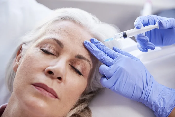 Beautician giving-mature female patient botox injection.